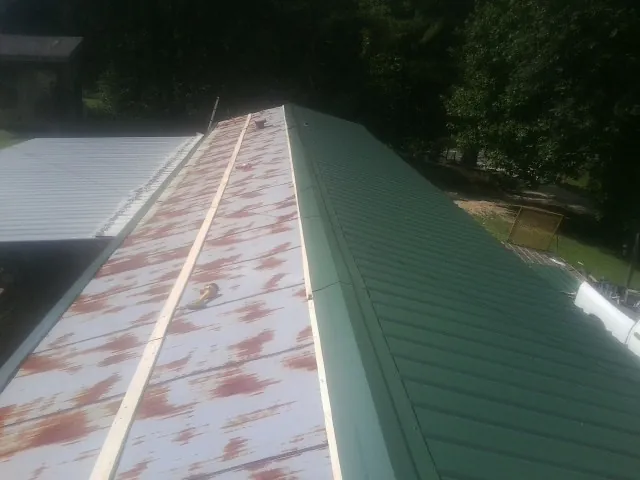 Old rusted panels beside newly installed green metal roofing — Wind Damage Roof Repair by Roofing Brothers in Land O Lakes