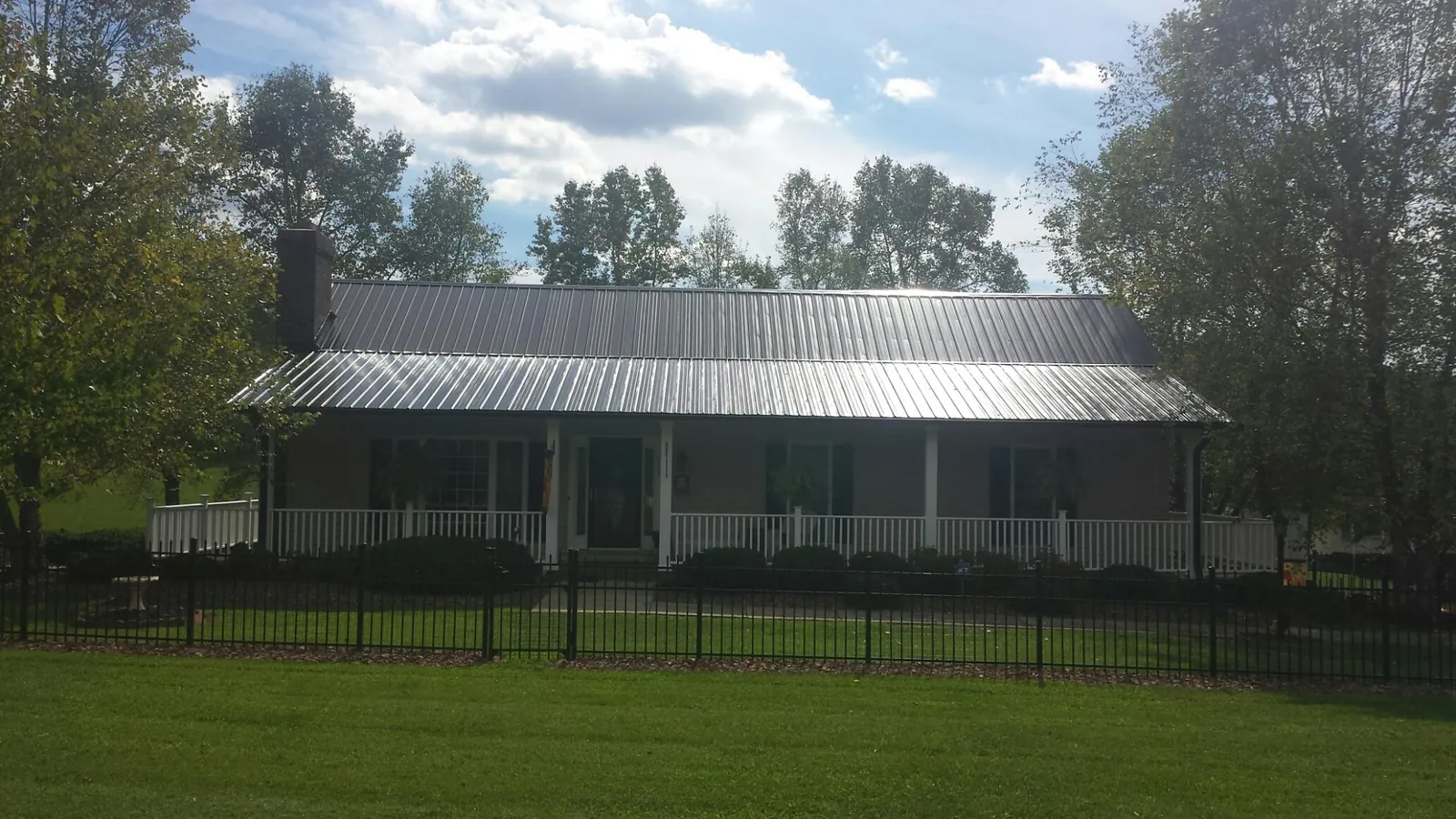 Gray metal roof on a brick ranch with a full width front porch — Gutter Guard Installation work by our crew in Land O Lakes