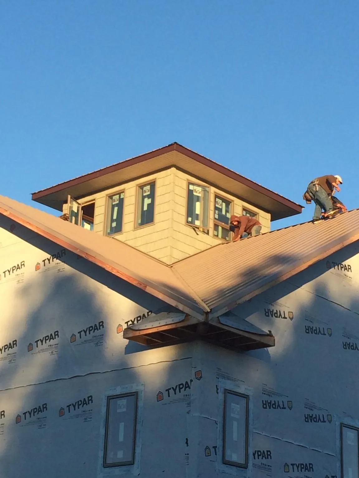 Roofers working around a rooftop cupola on a new metal roof at sunset — Roof Waterproofing in Land O Lakes by Roofing Brothers